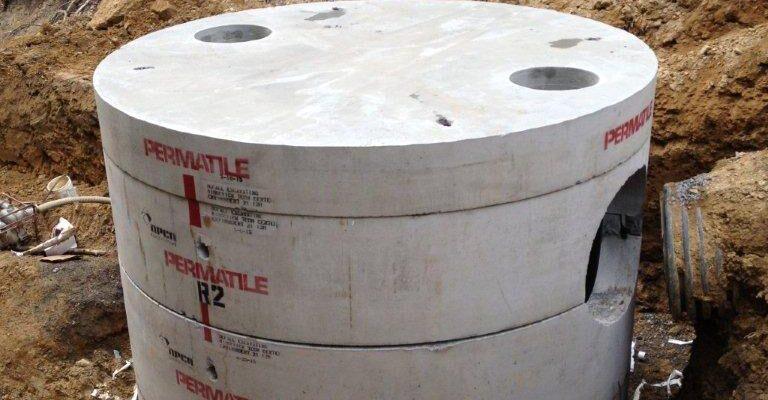 Precast concrete manhole installation in a construction site, partially buried in soil, showcasing durable engineering.