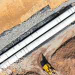 Aerial view of precast concrete pipes installed at a construction site with surrounding dirt and machinery.